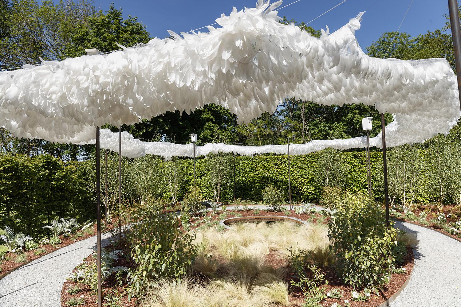 Its centerpiece is a canopy of 46,000 white goose feathers sewn onto cotton bias and attached via snap ties to a near-transparent mesh netting, hung by cables attached to steel poles.